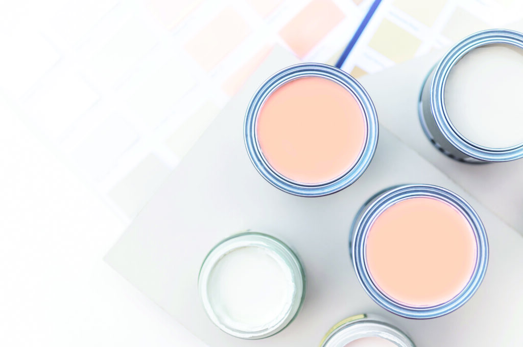 Tiny sample paint cans during house renovation, process of choosing paint for the walls, Peach Fuzz color of the year 2024, color charts on background